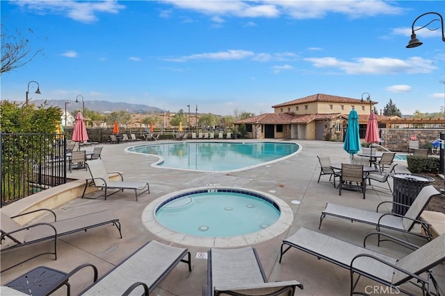 view of pool with a hot tub, a mountain view, and a patio