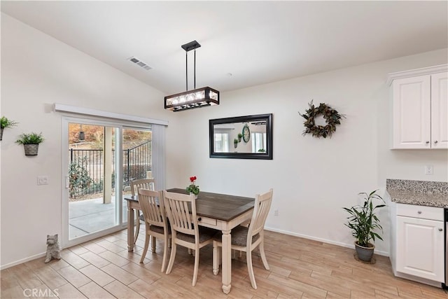 dining space featuring vaulted ceiling and light wood-type flooring