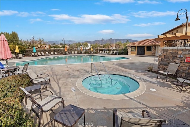 view of pool with a patio, a mountain view, and a community hot tub