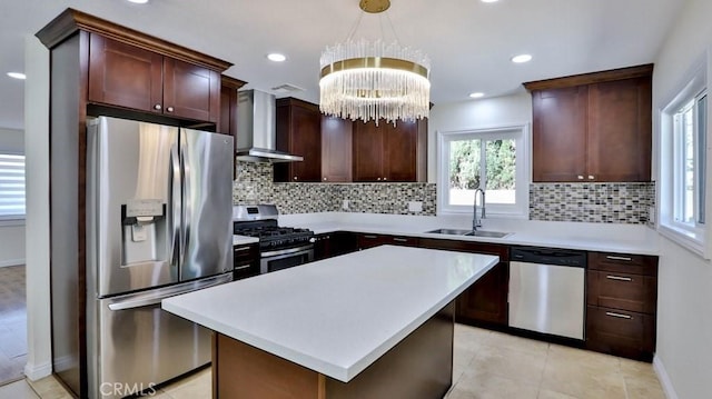 kitchen with appliances with stainless steel finishes, decorative light fixtures, sink, a center island, and wall chimney exhaust hood