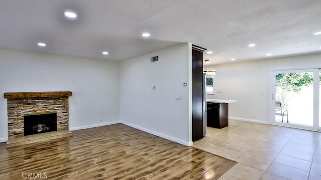 unfurnished living room with a stone fireplace and light hardwood / wood-style flooring