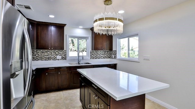 kitchen with decorative light fixtures, sink, backsplash, a center island, and stainless steel refrigerator with ice dispenser