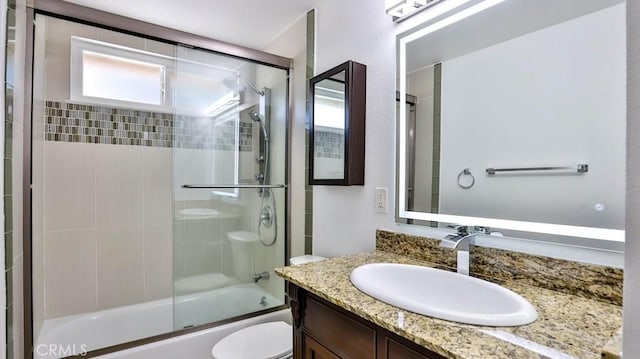 full bathroom with vanity, shower / bath combination with glass door, and toilet