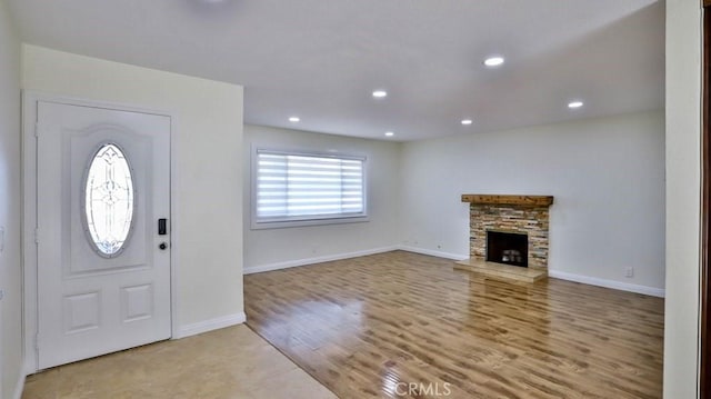 entrance foyer with a stone fireplace and light wood-type flooring