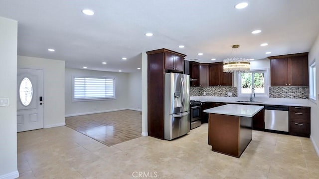 kitchen featuring sink, appliances with stainless steel finishes, a kitchen island, pendant lighting, and decorative backsplash