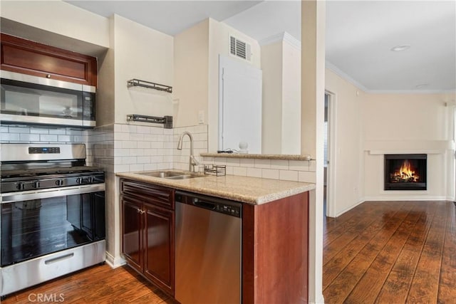 kitchen featuring sink, crown molding, appliances with stainless steel finishes, backsplash, and dark hardwood / wood-style floors