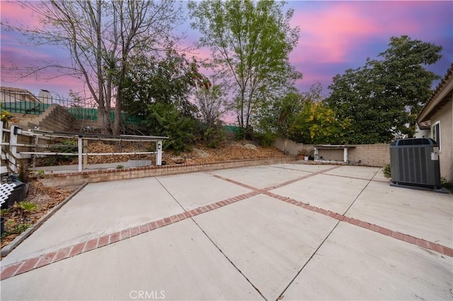 patio terrace at dusk featuring central AC unit