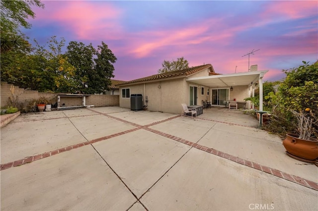 back house at dusk featuring central AC and a patio area