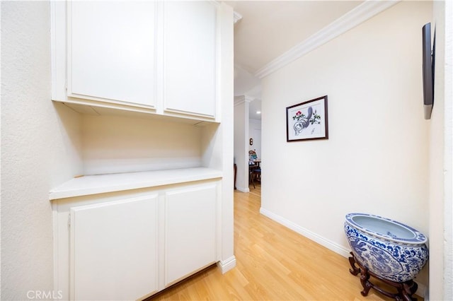 interior space with white cabinetry, crown molding, and light hardwood / wood-style flooring