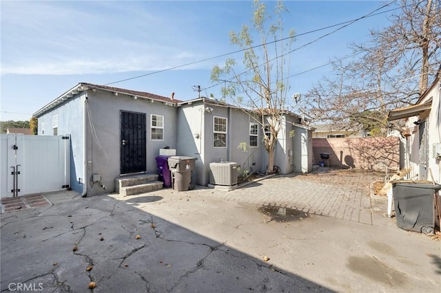 back of property with central AC and a patio area