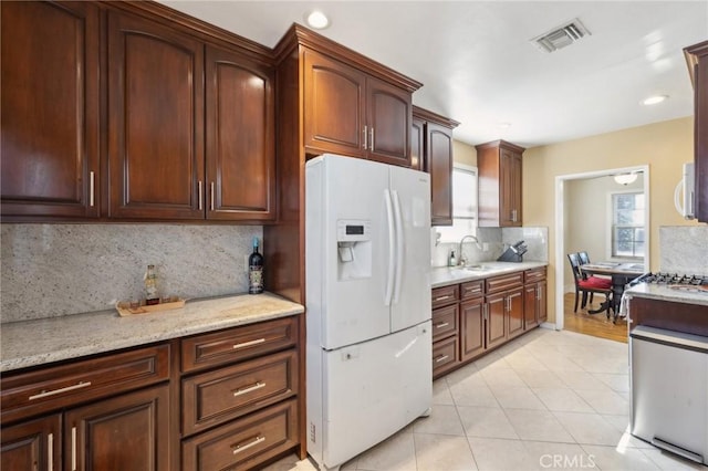 kitchen featuring sink, white appliances, tasteful backsplash, light stone countertops, and light tile patterned flooring