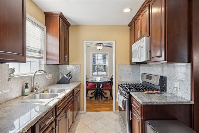 kitchen featuring a healthy amount of sunlight, stainless steel gas range, sink, and light stone countertops