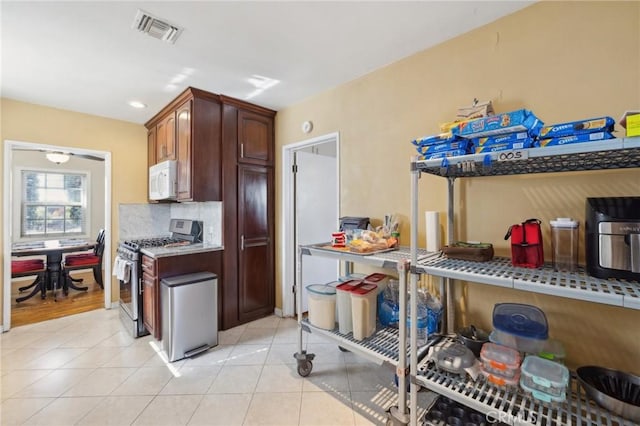 kitchen featuring light tile patterned floors, backsplash, and stainless steel range with gas cooktop