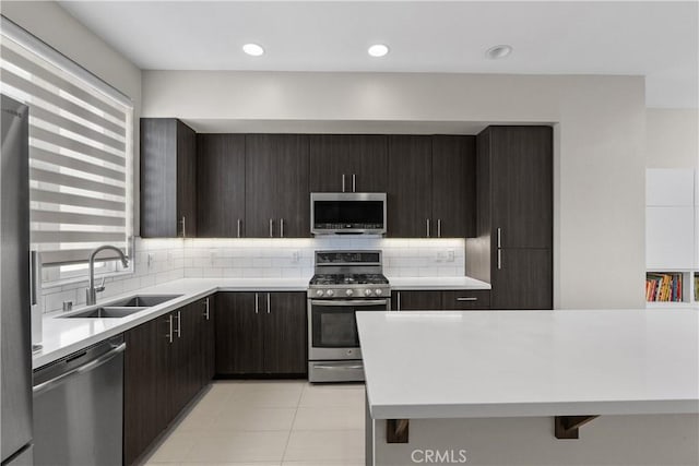 kitchen with stainless steel appliances, sink, light tile patterned floors, and decorative backsplash