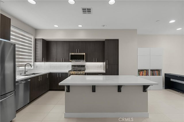 kitchen with sink, backsplash, a kitchen breakfast bar, stainless steel appliances, and a center island