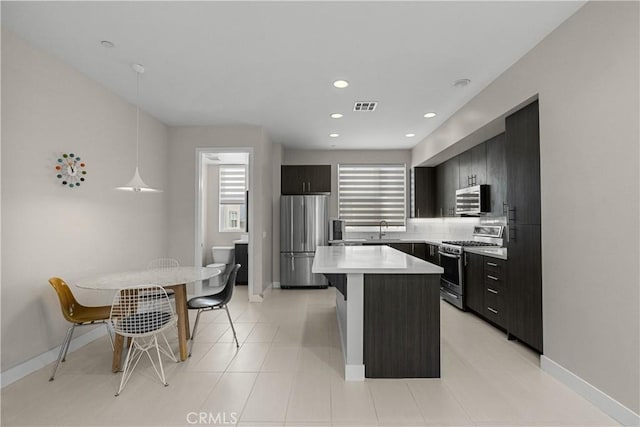 kitchen with sink, a kitchen island, stainless steel appliances, a kitchen bar, and decorative light fixtures