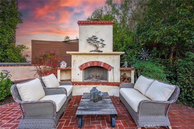 patio terrace at dusk with an outdoor living space with a fireplace