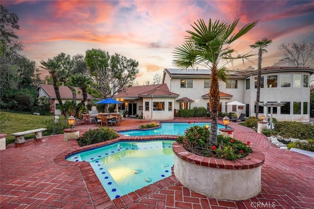 pool at dusk featuring a patio area