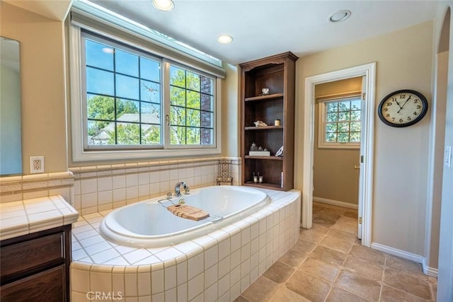 bathroom featuring tiled bath and vanity