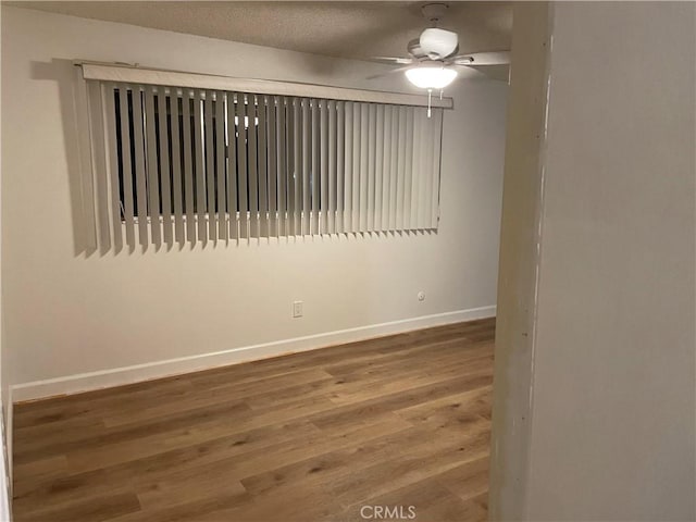 spare room with a ceiling fan, baseboards, and wood finished floors