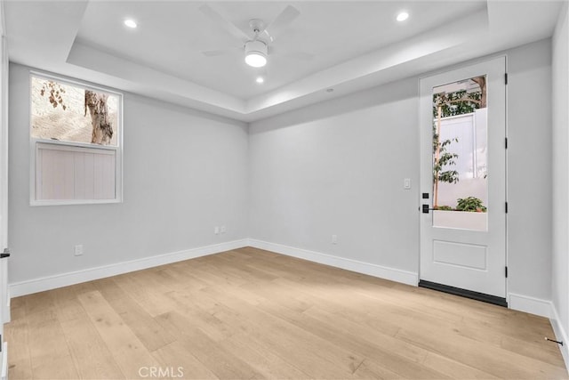 interior space featuring a tray ceiling, ceiling fan, and light wood-type flooring