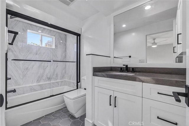 full bathroom featuring tile patterned flooring, enclosed tub / shower combo, vanity, ceiling fan, and toilet