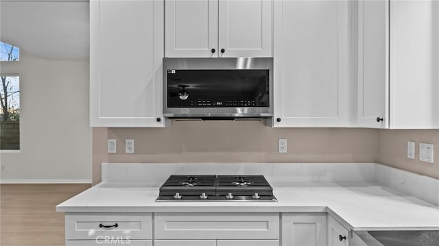 kitchen with white cabinetry, light stone counters, light hardwood / wood-style flooring, and stainless steel appliances