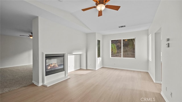 unfurnished living room featuring ceiling fan, a multi sided fireplace, lofted ceiling, and light hardwood / wood-style flooring