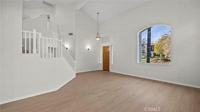 unfurnished living room with beam ceiling, high vaulted ceiling, and light wood-type flooring