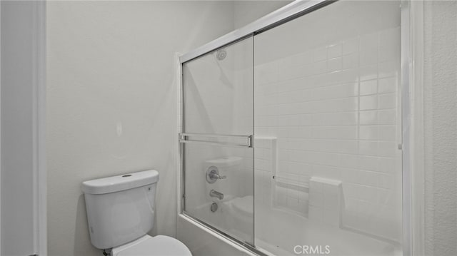 bathroom featuring enclosed tub / shower combo and toilet