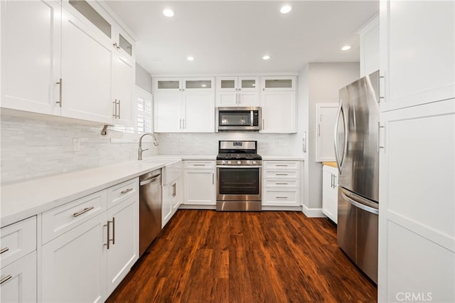 kitchen with appliances with stainless steel finishes, sink, decorative backsplash, and white cabinets