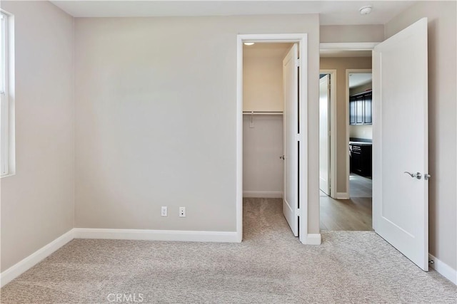 unfurnished bedroom with carpet, a spacious closet, and a closet