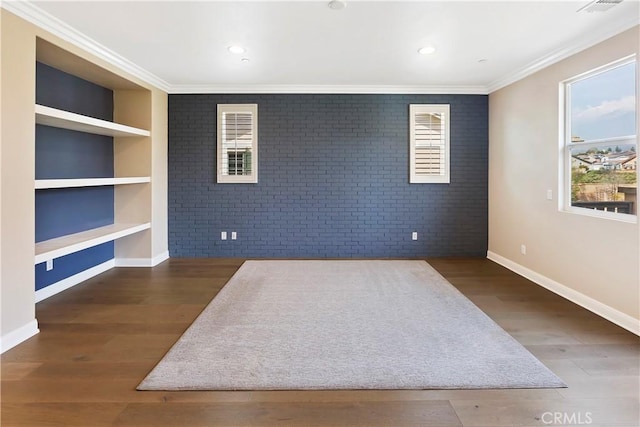 empty room with crown molding, brick wall, built in features, and dark hardwood / wood-style flooring