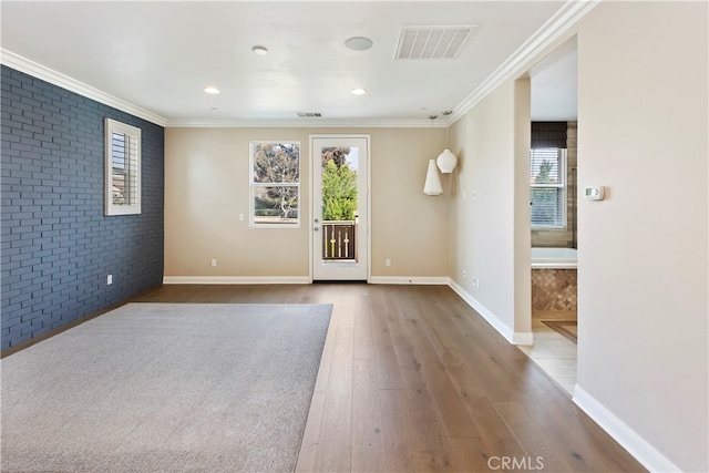 empty room featuring brick wall, ornamental molding, and wood-type flooring