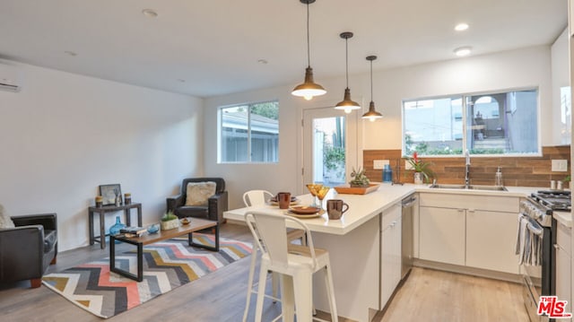 kitchen with sink, tasteful backsplash, light hardwood / wood-style flooring, kitchen peninsula, and stainless steel appliances