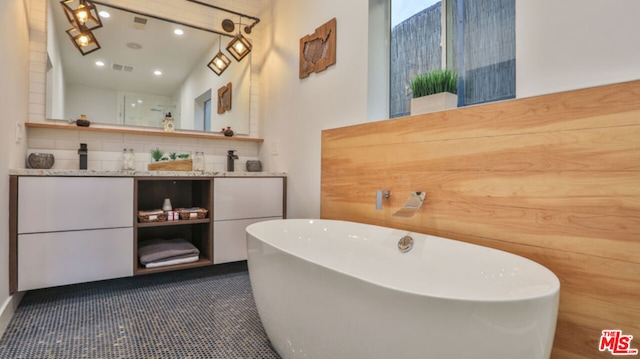 bathroom featuring vanity, backsplash, and a bathtub