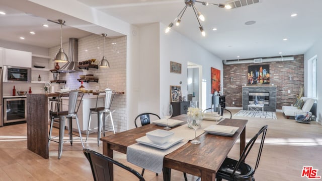 dining room featuring bar area, light hardwood / wood-style floors, beverage cooler, and brick wall