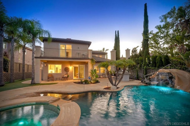 pool at dusk featuring an in ground hot tub, pool water feature, and a patio