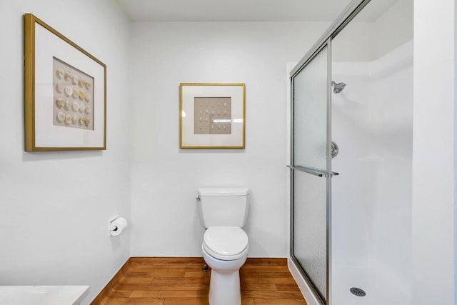 bathroom with a shower with shower door, hardwood / wood-style floors, and toilet