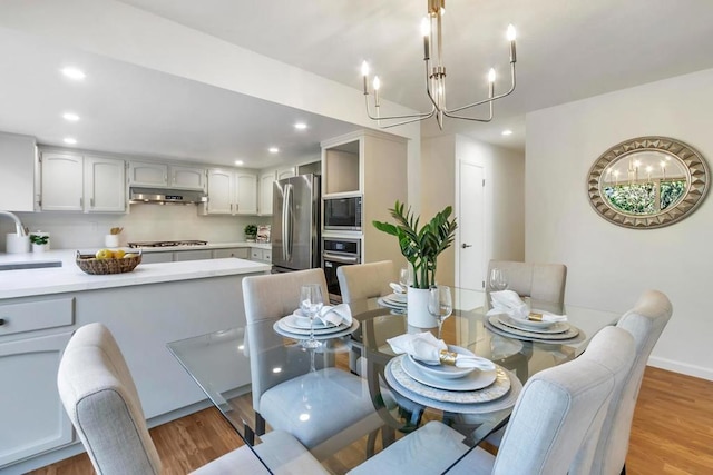 dining area featuring sink, a chandelier, and light hardwood / wood-style floors