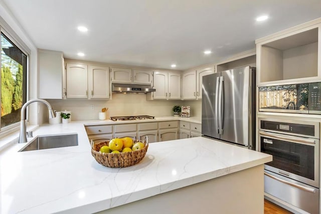 kitchen featuring stainless steel appliances, light stone countertops, sink, and backsplash