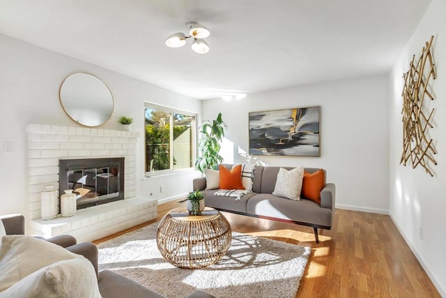 living room featuring a brick fireplace and light hardwood / wood-style flooring