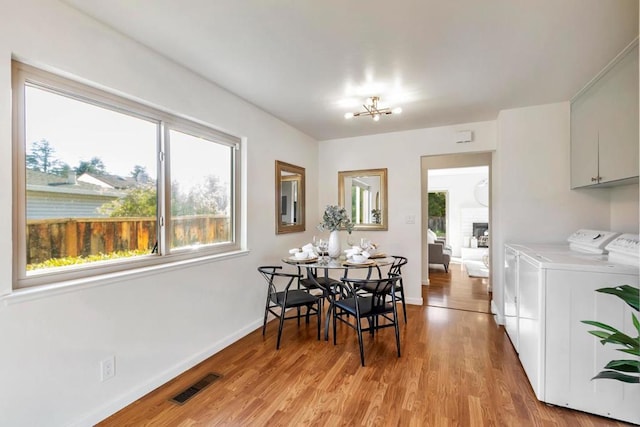 dining room featuring light hardwood / wood-style flooring, a notable chandelier, and washer and clothes dryer