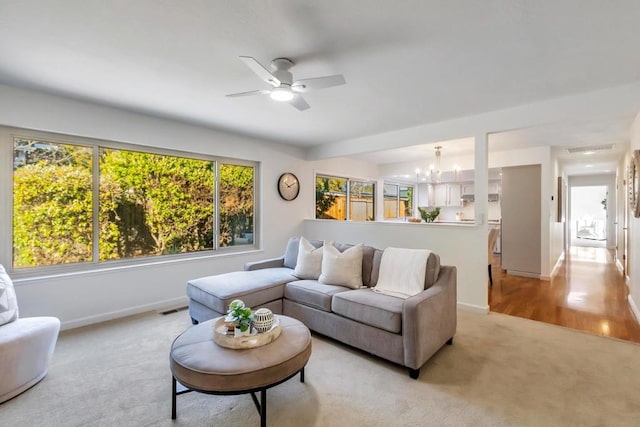 living room featuring ceiling fan with notable chandelier and light colored carpet