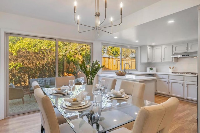 dining area with plenty of natural light, sink, light hardwood / wood-style flooring, and a notable chandelier