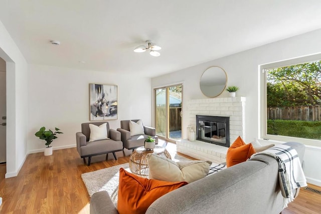 living room with a brick fireplace and light wood-type flooring