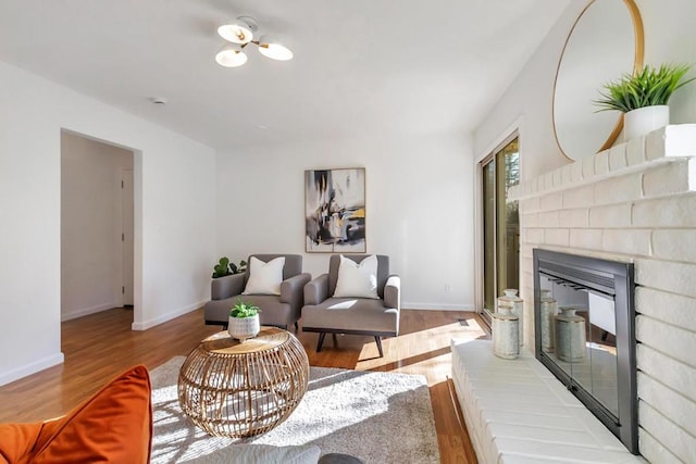 living room with a brick fireplace and light wood-type flooring