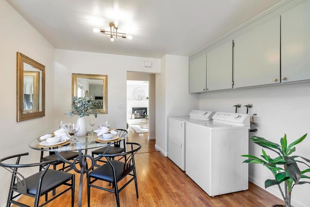 clothes washing area with cabinets, separate washer and dryer, and light hardwood / wood-style floors