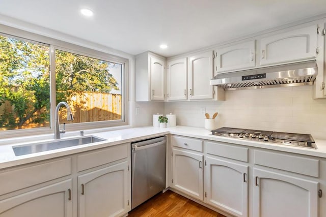 kitchen featuring hardwood / wood-style floors, sink, white cabinets, decorative backsplash, and stainless steel appliances