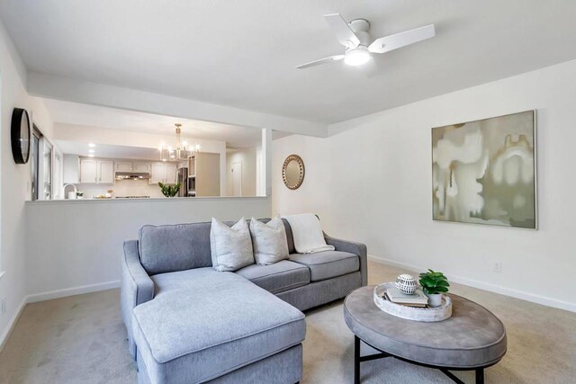 carpeted living room featuring ceiling fan with notable chandelier